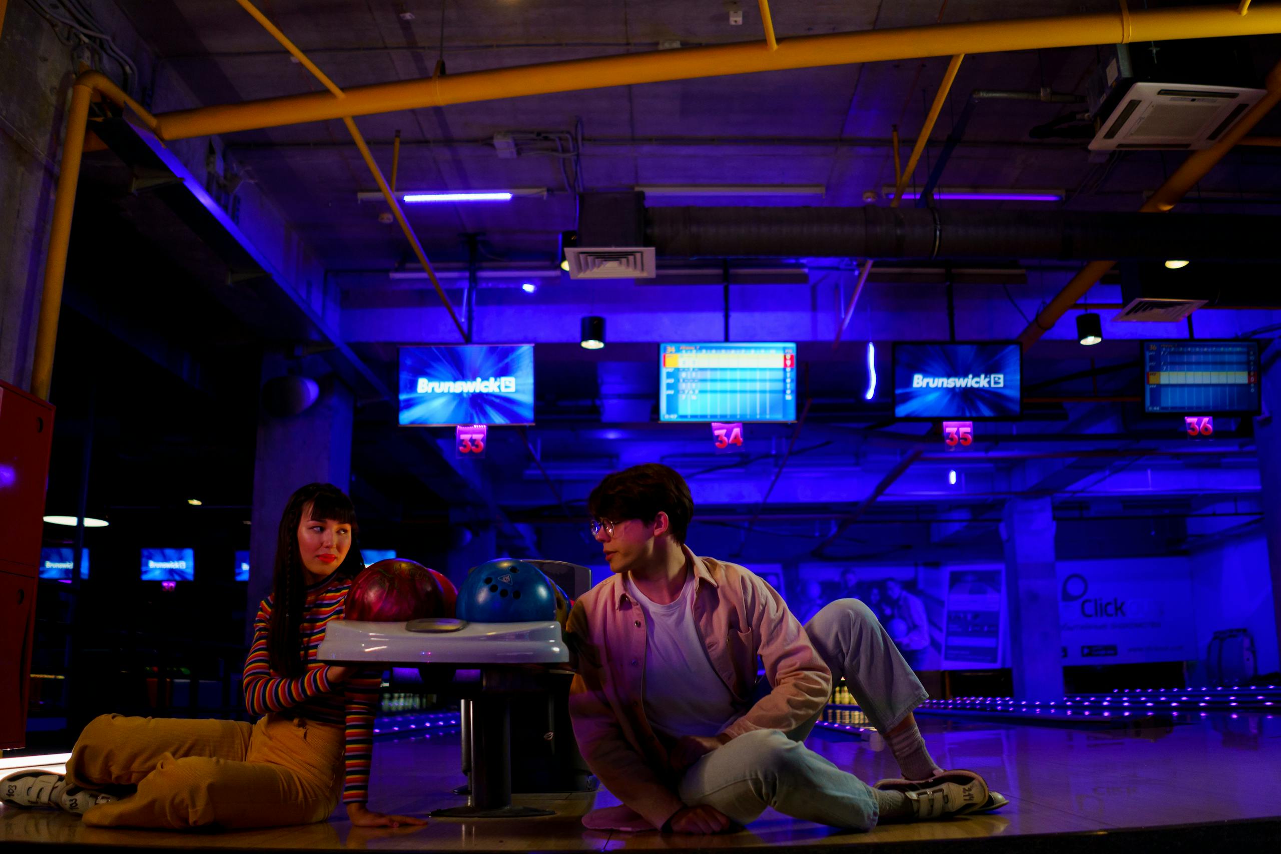 Young Couple sitting on a Bowling Area while looking at each other